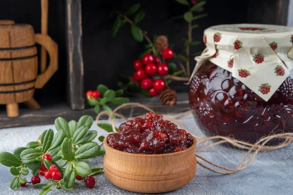 Mermelada de Lingonberry o salsa en un tazón de madera y en un frasco de vidrio — Foto de Stock