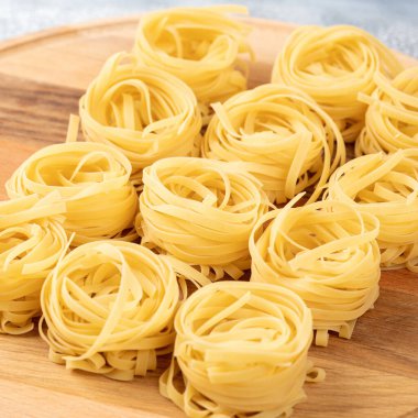 Pişmemiş kuru tagliatelle makarna yuvası. Tahta üzerinde. Boşluğu kopyala