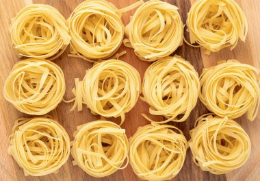 Pişmemiş kuru tagliatelle makarna yuvası. Tahta üzerinde. Boşluğu kopyala