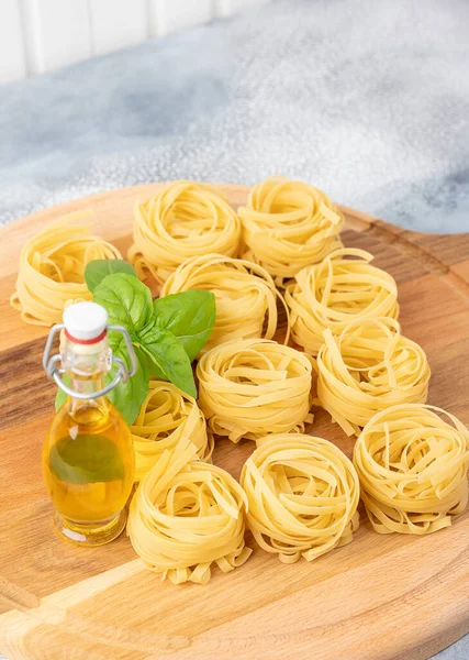 Uncooked Dry Tagliatelle Pasta Nest Wooden Board Basil Olive Oil — Stock Photo, Image