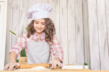 Kız mutfakta. Çörek pişirme işlemi. Küçük bir aşçı. Beyaz kap.