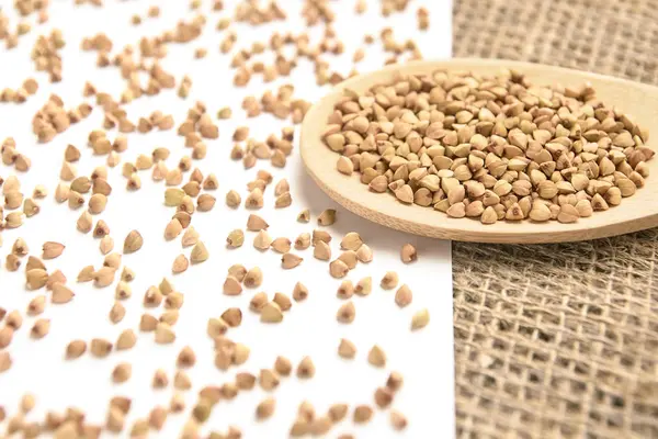 Tahta kaşık. Dağınık buğday taneleri. Beyaz arka plan.