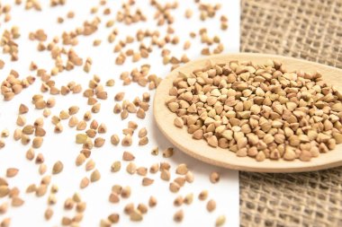 Dağınık buğday taneleri. Tahta kaşık. Beyaz arka plan.