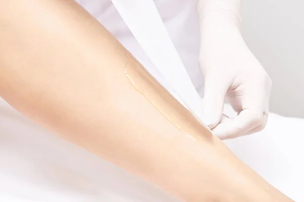 Waxing woman leg. Sugar hair removal. laser service epilation. Salon wax beautician procedure.