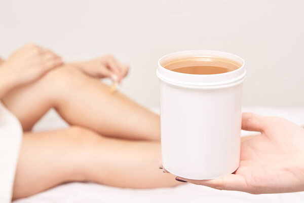Waxing woman leg. Sugar hair removal. laser service epilation. Salon wax beautician procedure.