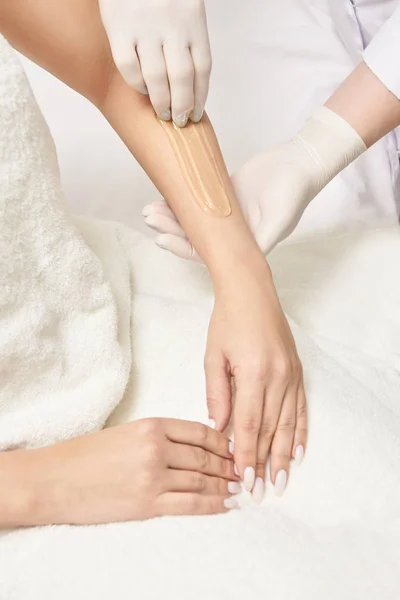 Sugar hair removal from woman body. Wax epilation spa procedure. Procedure beautician female. Forearm.