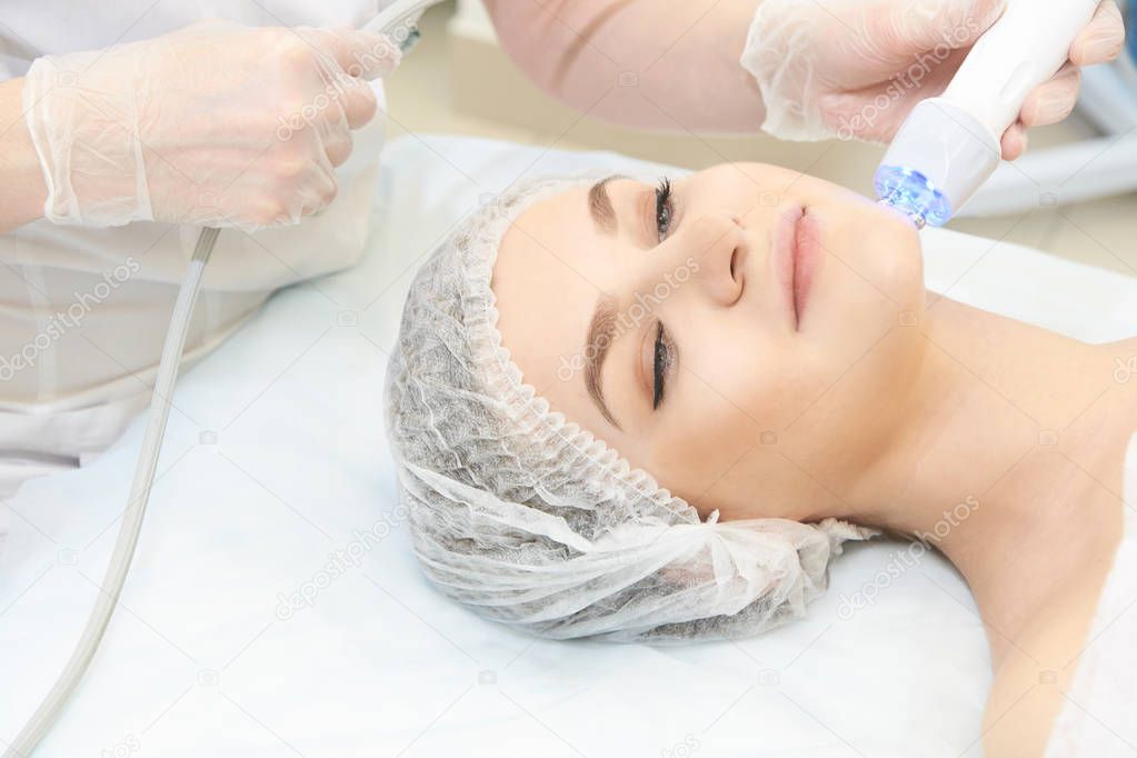 Microcurrent facial dermatology procedure. Model. Aesthetic radiofrequency treatment. Micro current cosmetology massage.