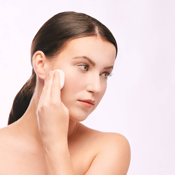 Young girl remove cosmetic from face. skin care with cotton pad.