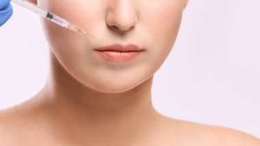 Yüz iğnesi. Genç kadın kozmetoloji prosedürü. Doktor eldivenleri.