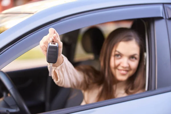 Young woman in car. Ride instruction. Automobile loan. Hand with key.