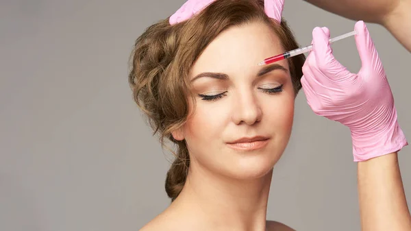 Face needle injection. Young woman cosmetology procedure. Doctor gloves.