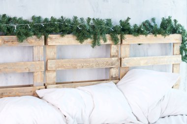 Beyaz yastıklar. Yatak başı. Yeşil çam dalı.