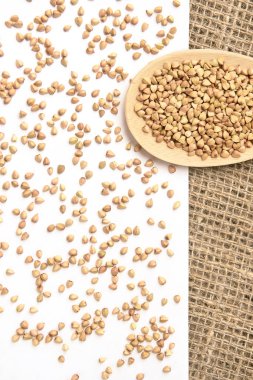 Dağınık buğday taneleri. Tahta kaşık. Beyaz arka plan.