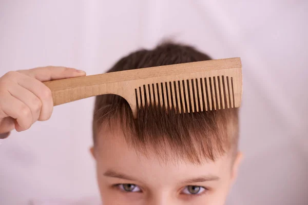 Serious view. Wooden comb. Bright interior. Horizontal.