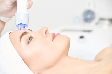 Microcurrent ışık estetik yordamı. Güzellik kız yüz. Kozmetik makine. Doktor eller. İki mikro top. Kırışıklık Azaltma.