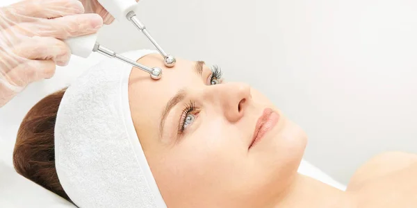 Microcurrent esthetics procedure. Beauty girl face. Cosmetology machine. Doctor hands. Two micro balls. Wrinkle reduction.