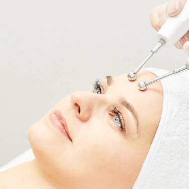 Microcurrent estetik yordamı. Güzellik kız yüz. Kozmetik makine. Doktor eller. İki mikro top. Kırışıklık Azaltma