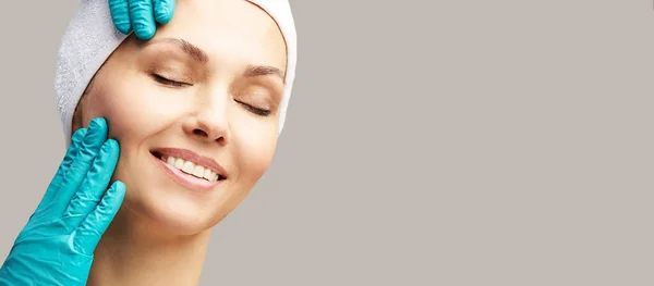 Kadın derma tedavi gençleştirmek. Eldivenli doktor kadın yüzüne dokunur. Kozmetoloji güzel portre. Yüz enjeksiyonu hastası