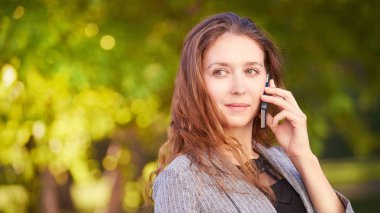 Genç mutlu kız cep telefonu konuşuyor. Telefon dolaşıyor. Akıllı telefonu olan insanlar. Sonbahar arka planı