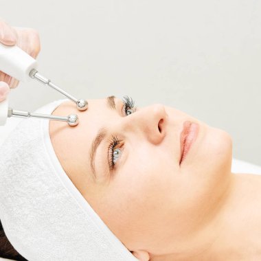 Microcurrent estetik yordamı. Güzellik kız yüz. Kozmetik makine. Doktor eller. İki mikro top. Kırışıklık Azaltma