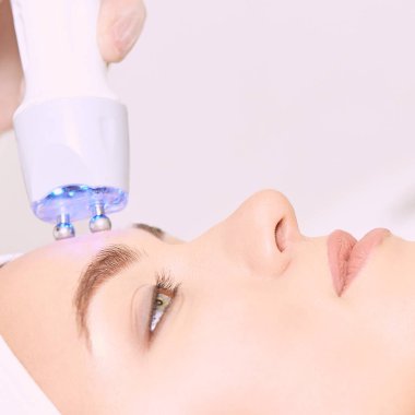 Microcurrent ışık estetik yordamı. Güzellik kız yüz. Kozmetik makine. Doktor eller. İki mikro top. Kırışıklık Azaltma