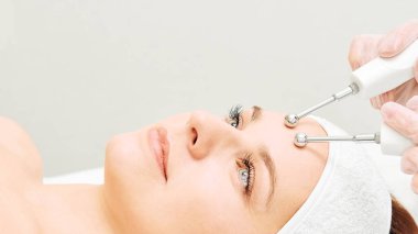 Microcurrent estetik yordamı. Güzellik kız yüz. Kozmetik makine. Doktor eller. İki mikro top. Kırışıklık Azaltma