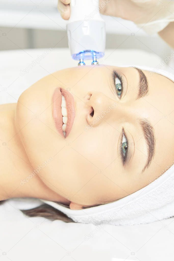 Light infrared therapy. Cosmetology head procedure. Beauty woman face. Cosmetic salon device. Facial skin rejuvenation