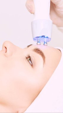 Microcurrent ışık estetik yordamı. Güzellik kız yüz. Kozmetik makine. Doktor eller. İki mikro top. Kırışıklık Azaltma