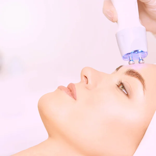 Microcurrent light esthetics procedure. Beauty girl face. Cosmetology machine. Doctor hands. Two micro balls. Wrinkle reduction — Stock Photo, Image