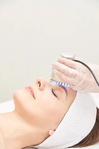 Infrarood Lichttherapie. Cosmetologie hoofd procedure. De gezicht van de vrouw van de schoonheid. Cosmeticastudio apparaat. Verjonging van de gezichtshuid — Stockfoto