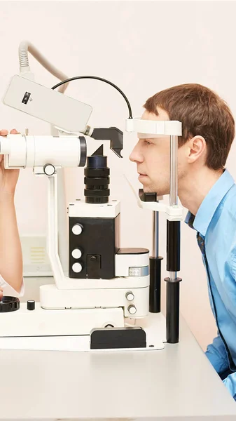 眼科医の検査視力回復乱視チェックの概念。眼科診断装置。クリニックで美少女の肖像画。男性患者 — ストック写真