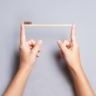 Bambu diş fırçasıyla el ele tutuşun. Gri arkaplan