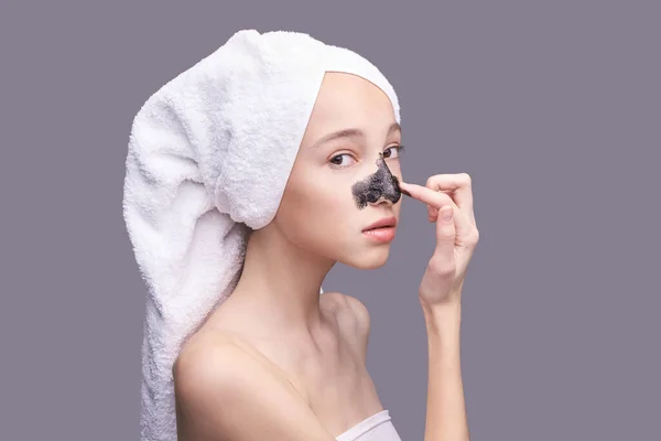 Menina aplicando máscara preta — Fotografia de Stock