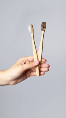 Bambu diş fırçasıyla el ele tutuşun. Gri arkaplan