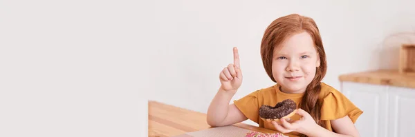 Little girl eating round doughnut. Sweet desert. Unhealthy food. Pointing — Stock Photo, Image