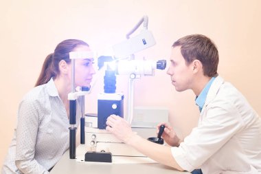 Optisyen doktor, erkek hastayla birlikte muayene laboratuvarında. Erkekler