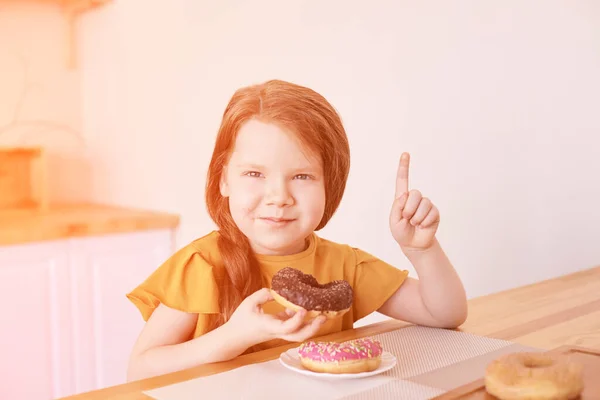 Dziewczynka je okrągłe pączki. Słodka pustynia. Niezdrowe jedzenie. Wskazanie — Zdjęcie stockowe