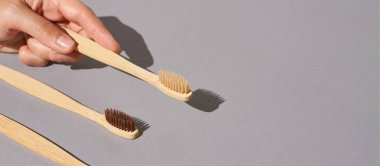 Bambu diş fırçasıyla el ele tutuşun. Gri arkaplan