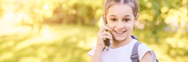 Uma menina gira a falar. Segure o telefone perto do rosto — Fotografia de Stock