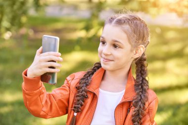 Küçük kız selfie çekiyor. Mutlu güzel çocuk. Yeşil açık arkaplan