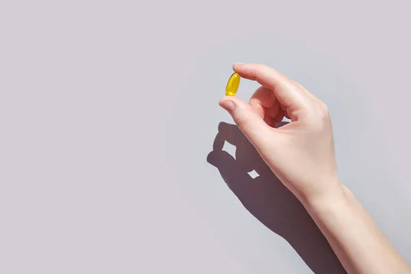 Omega3 gel capsule. Yellow vitamin. Yand holding drug