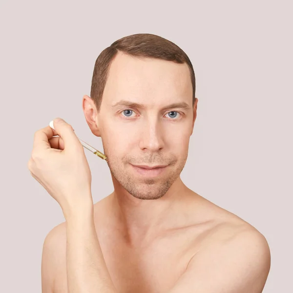 Huidverzorgingsroutine. Olie pipet in de buurt van mannelijke gezicht — Stockfoto