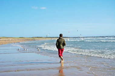 okyanus kıyısında yürüyen adam