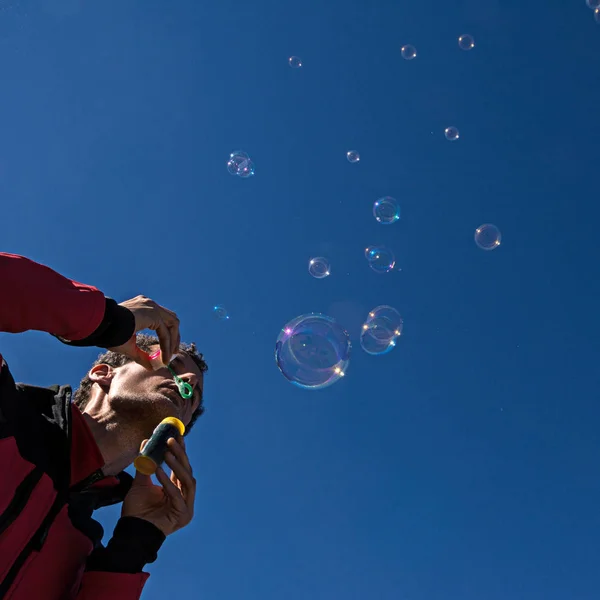 Muž Barevnými Reflexní Mýdlové Bubliny Plovoucí Modré Obloze — Stock fotografie