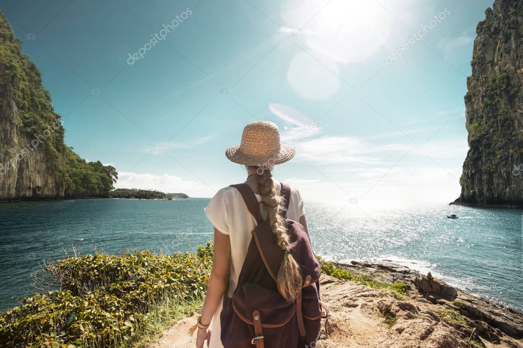 girl traveler wearing straw hat in rocky marine landscape