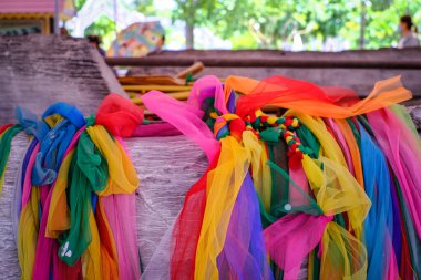 Tayland tapınağındaki antik teknede renkli çiçek çelenkleri.