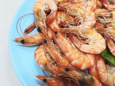 Lezzetli haşlanmış karides mavi bir tabağa konur.