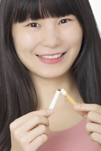 美しいアジア女性タバコを破壊しながら笑みを浮かべて白い背景に分離されて禁煙を終了するには — ストック写真