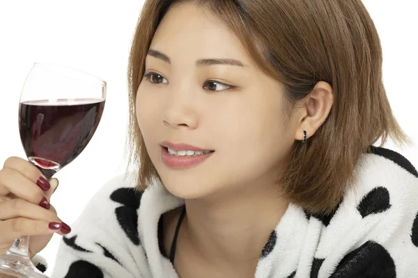 中国のアメリカ人女性が白い背景に分離した赤ワインを飲んでベッドに敷設 — ストック写真