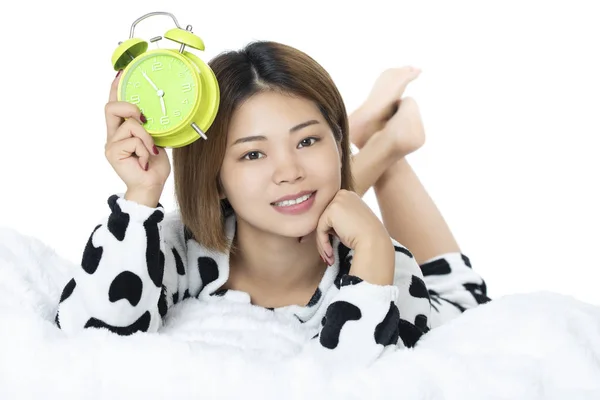 白い背景に分離された緑の目覚まし時計で黒と白のパジャマを着てベッドに横になっている中国の女性 — ストック写真